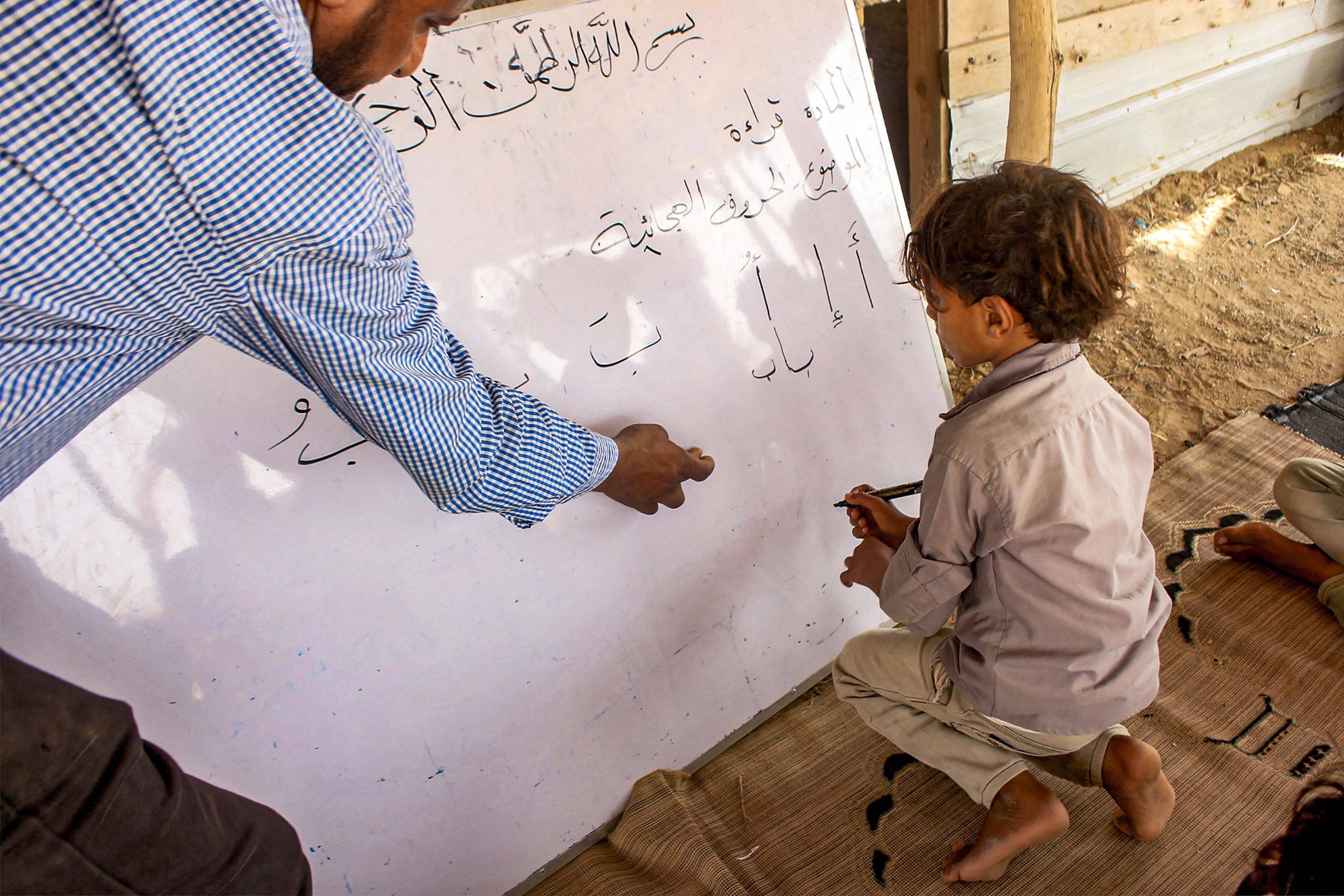 A Yemeni teacher gives lessons to children in a straw-built school (archive)